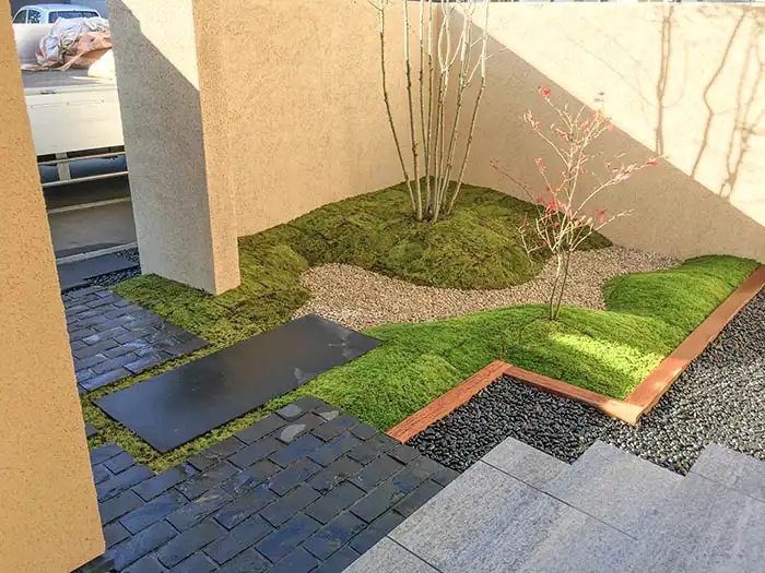 直線的な延段の周りを苔が中和するシンプルでモダンなアプローチ