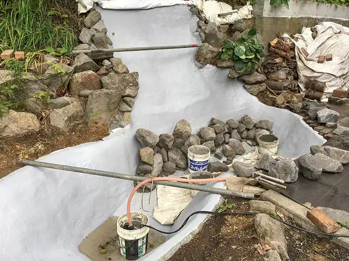 滝の防水層施工完了後の、石組みの序盤の様子